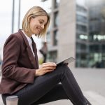 Smiling young businesswoman using tablet in the city